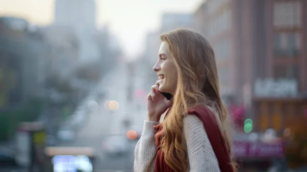 Onnellinen nainen pitelee puhelinta kävellessään. Upea tyttö puhuu puhelimessa kadulla. — kuvapankkivalokuva