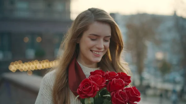สาวที่มีความสุข เดินไปพร้อมกับช่อดอกไม้ ผู้หญิงสวยถือดอกกุหลาบแดงบนถนน . — ภาพถ่ายสต็อก