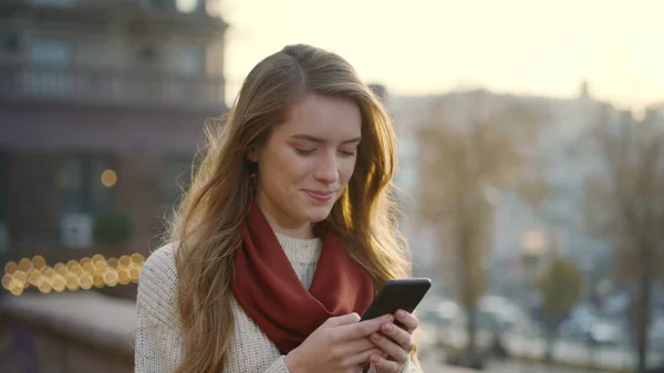 Happy lány sms-ezik a mobiljával a szabadban. Vidám nő kezében telefon — Stock Fotó
