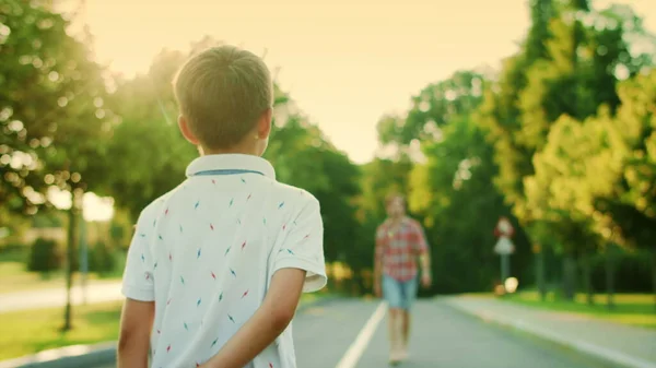 Ένα μικρό αγόρι που βγαίνει στο δρόμο. Όμορφος άντρας και αγόρι βαδίζουν ο ένας προς τον άλλο. — Φωτογραφία Αρχείου