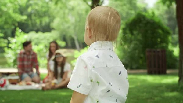 Веселый малыш бегает в парке. Дети устраивают пикник с родителями в лесу — стоковое фото
