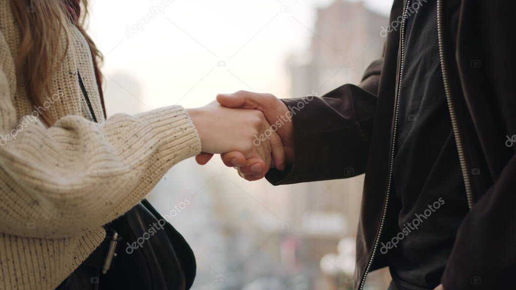 Unrecognizable couple handshaking outside. Closeup people hands holding outdoors