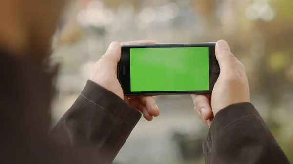 Man hands touching cellphone with greenscreen. Unknown guy holding mock up phone
