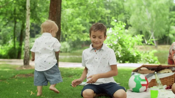 Mannen sitter på filt med barn i parken. Barn leker med såpbubblor — Stockfoto