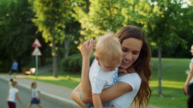 Anne dışarıda oğlunu tutuyor. Kadın ve çocuk sokakta dönüyorlar.