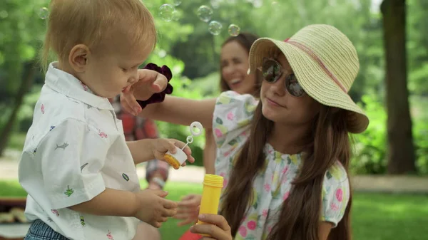 Soeur qui s'occupe du petit frère. Parents regardant frères et sœurs dans le parc — Photo