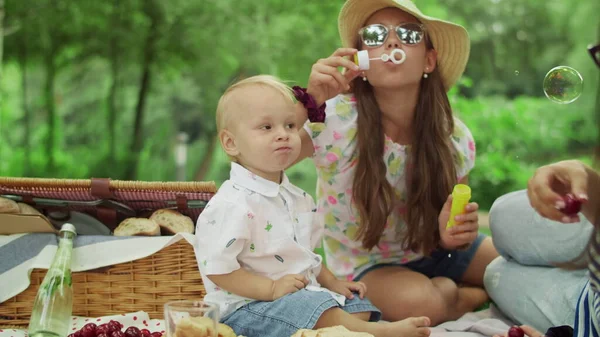 A criança a comer cerejas no piquenique. Mãe com crianças relaxando na floresta — Fotografia de Stock