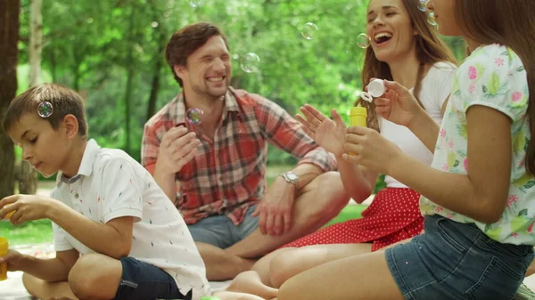 Barn leker med såpbubblor i skogen. Familjen spenderar tid tillsammans i parken — Stockfoto