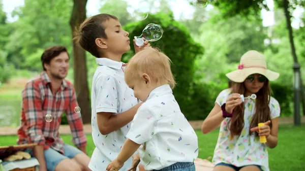 Barn som blåser bubblor utomhus. Föräldrar tillbringar tid med barn i parken — Stockfoto