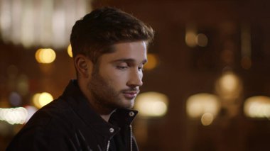 Karanlık sokakta duran yakışıklı hippi çocuk. Ciddi bir adam etrafa bakıyor.