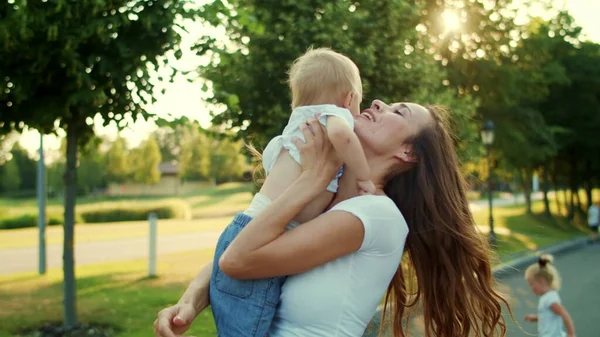 Een vrouw op straat met een kleine jongen. Moeder houdt zoon op handen in het park — Stockfoto