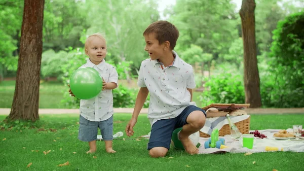 Два брата проводят время в летнем парке. Братья и сестры играют с мячом на открытом воздухе — стоковое фото