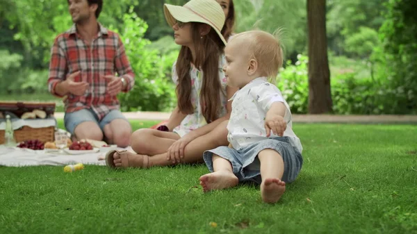 Милый малыш падает на траву в парке. Семейные выходные вместе — стоковое фото