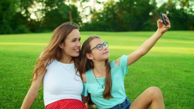 Kız ve kadın parkta akıllı telefondan selfie çekiyorlar. Cep telefonu kullanan aile