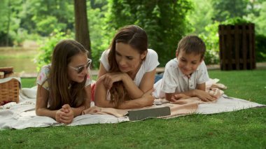 Tablette film izleyen gülümseyen bir aile. Aile dışarıda bilgisayar kullanıyor
