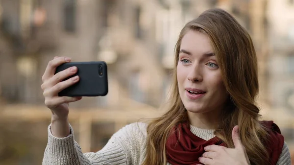 Chica sonriente teniendo videollamada con teléfono al aire libre. Mujer feliz videochat . — Foto de Stock