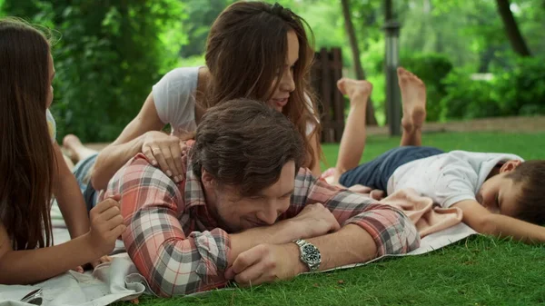 Família deitada em cobertor no parque. Crianças felizes com os pais relaxando fora — Fotografia de Stock