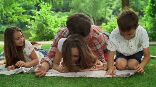 Семья веселится в парке. Дети с родителями лежат на одеяле в лесу — стоковое фото