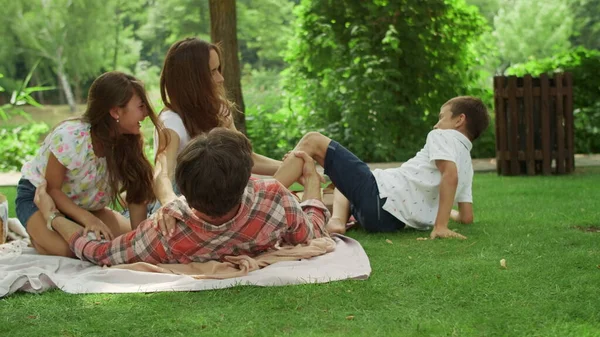 Eltern spielen mit Kindern im Park. Kinder und Eltern liegen auf Decke — Stockfoto