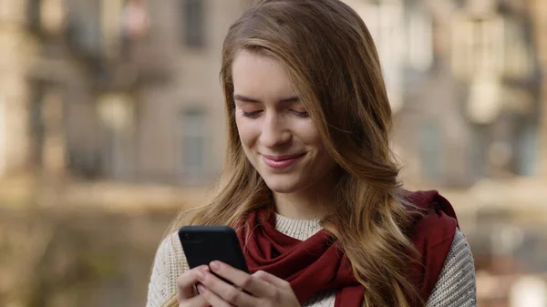 Mulher feliz comunicando por telefone ao ar livre. Menina alegre lendo telefone mensagem . — Fotografia de Stock