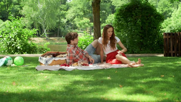 Happy woman and man having romantic date in park. Couple sitting on blanket — Stock Photo, Image