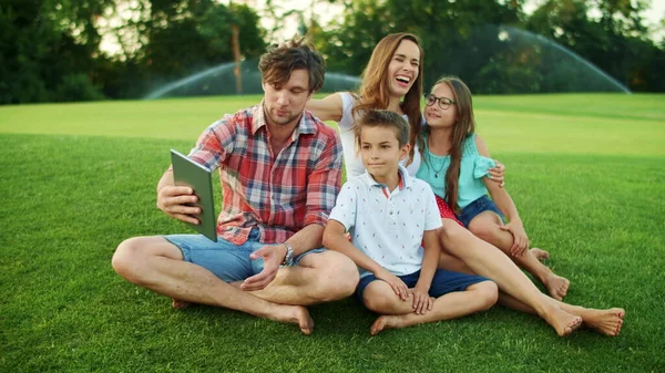 Família conversando por vídeo chat no pad no parque. Família usando comprimido — Fotografia de Stock