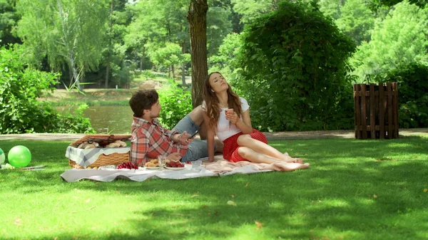 Couple pique-niquer dans le parc. Femme et homme souriants utilisant des smartphones à l'extérieur — Photo