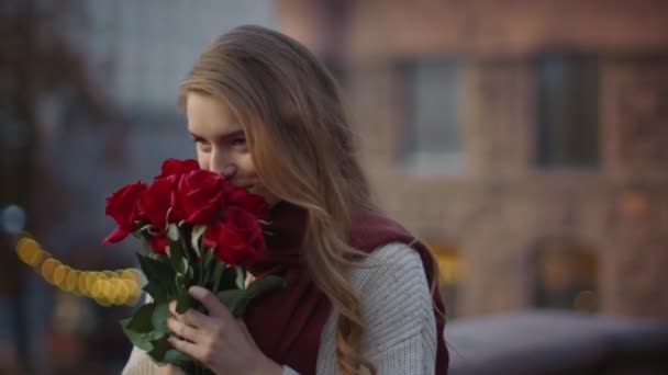 Doce menina cheirar flores do buquê fora. Mulher bonito carregando rosas na rua — Vídeo de Stock