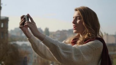 Sokakta akıllı telefon kullanan güzel kız. Tatlı kadın telefonla selfie çekiyor.