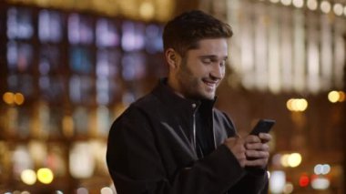 Heyecanlı adam sokakta cep telefonuna mesaj atıyor. Dışarıda telefon kullanan neşeli bir adam..