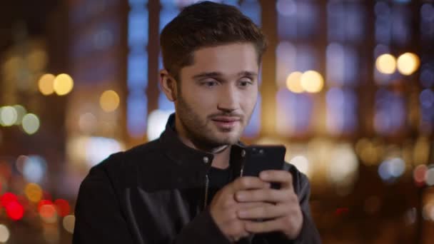 Vreugdevolle man leest boodschap op mobiele telefoon buiten. Jongen op zoek telefoon scherm — Stockvideo