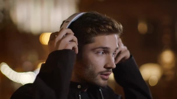 Hombre excitado bailando con auriculares en la calle oscura de la ciudad. Chico feliz disfrutando de la música . — Vídeos de Stock