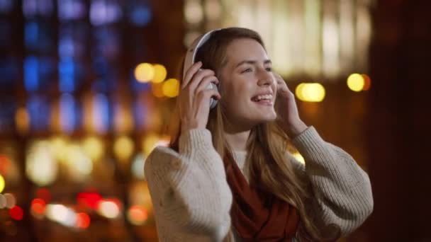 Menina sorrindo ouvir fones de ouvido música ao ar livre. Mulher feliz se divertindo lá fora — Vídeo de Stock