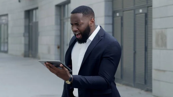 Geschäftsmann schaut auf dem Tablet-Bildschirm auf der Straße. Afro mann mit kissen outdoor — Stockfoto