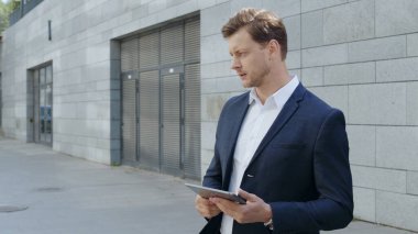 Sokakta tablet üzerinde çalışan bir iş adamı. Müdür sokakta ortağını bekliyor.