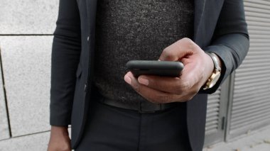 İş adamı dışarıda cep telefonuyla internette geziniyor. Akıllı telefon kullanan bir yönetici