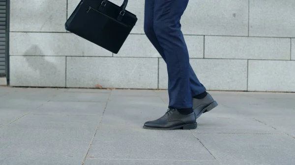 Geschäftsmannfüße tanzen allein auf der Straße. Mitarbeiter hält Aktentasche in der Hand — Stockfoto