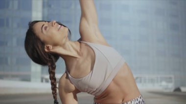 Kadın sokakta ters savaşçı yoga pozu veriyor. Dışarıda elini uzatan bir kadın.