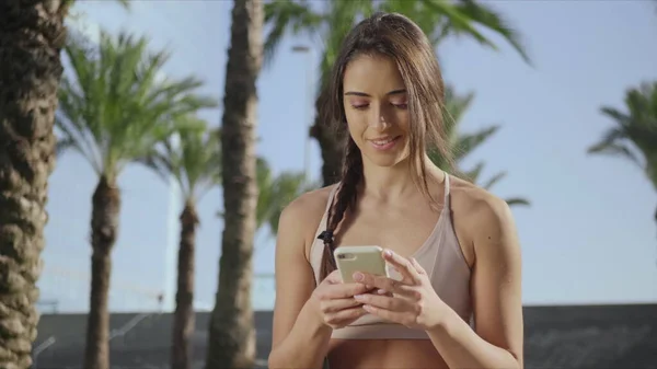 Entrenador de yoga con smartphone en el parque después del entrenamiento.Lady escribiendo por teléfono en el parque — Foto de Stock