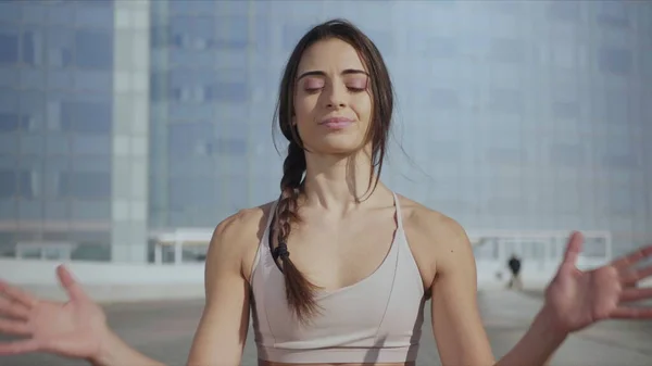 Mulher sorridente sentada em lótus posar na rua urbana.Fit menina meditando ao ar livre — Fotografia de Stock