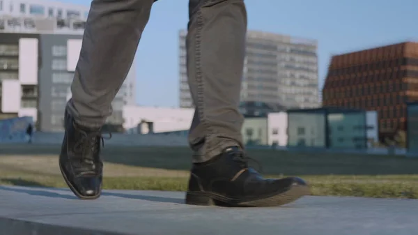 Unrecognized businessman legs walking on street. Worker feet going on street