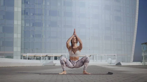 Жінка робить гірлянду позу на йога килимок на вулиці. Йога-тренер вправи зовні — стокове фото