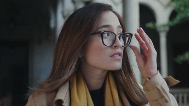 Üniversite koridorunda yürüyen bir öğrenci. İş kadını gözlük takıyor