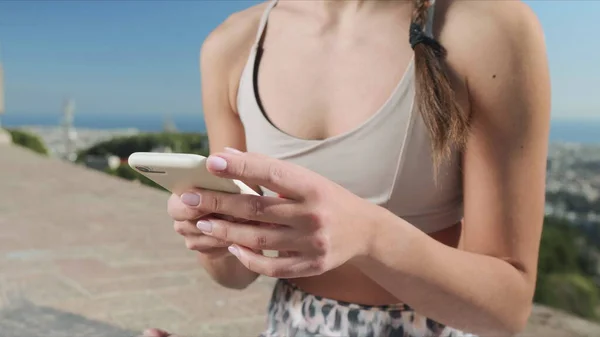 Desportista usando smartphone após treino ao ar livre. Mulher mãos digitando no telefone — Fotografia de Stock