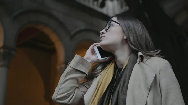 Kvinna pratar på smartphone utomhus. Affärskvinna kontrollerar tiden på armbandsur — Stockfoto