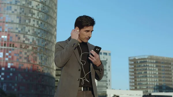 Geschäftsmann, der mit Kopfhörern auf der Straße läuft. Mitarbeiter mit Ohrhörern draußen — Stockfoto