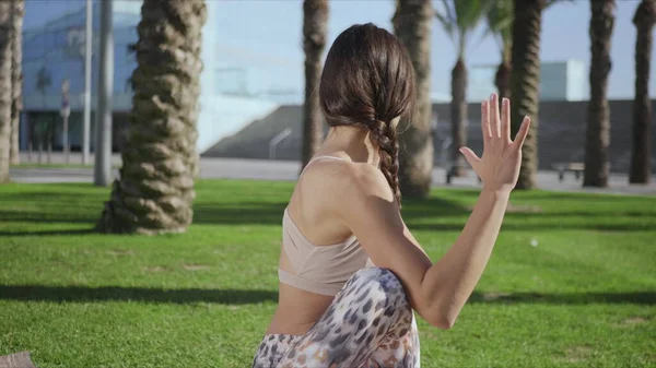 Una mujer sentada posando sobre una alfombra. Chica realizando yoga en el parque —  Fotos de Stock