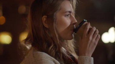 Sakin kız sokakta kahve içiyor. Rahatlamış bir kadın sıcak bir şeyler içiyor.