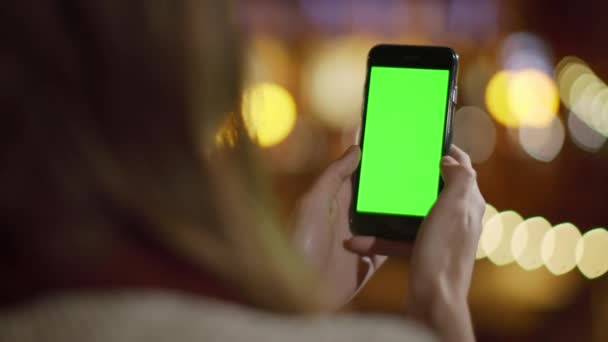 Руки девушки прокручивают макет телефона на улице. Женщина смотрит телефон зеленый экран. — стоковое видео