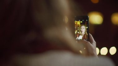 Bilinmeyen kız dışarıda selfie çekiyor. Neşeli kadın telefon kamerasına bakıyor..